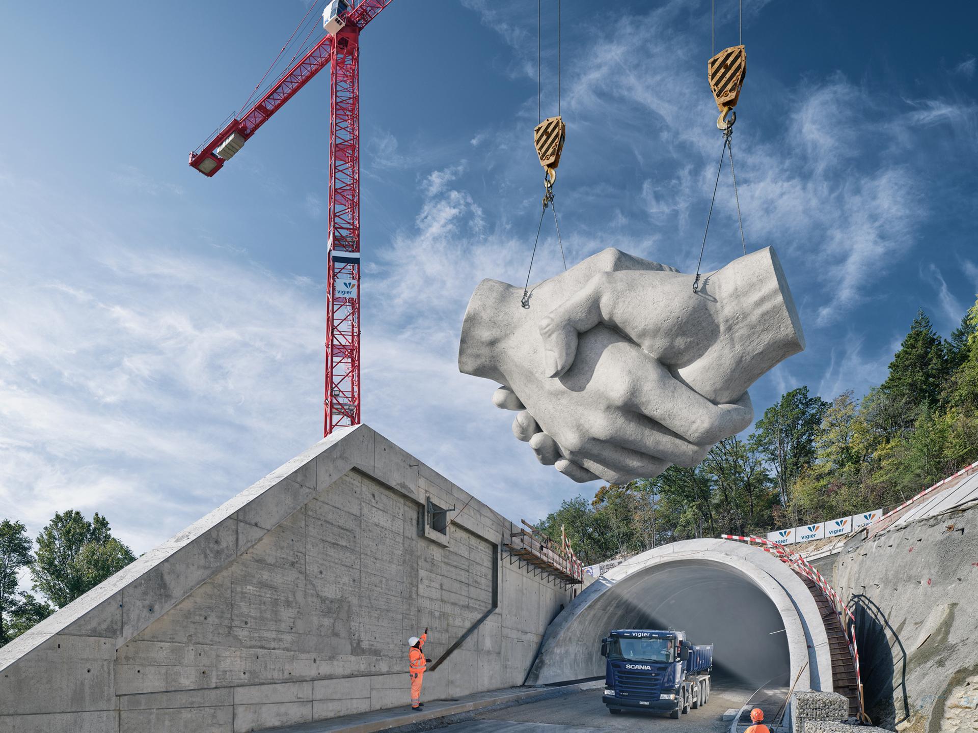 Das Keyvisual von Vigier Holding zeigt eine Betonskulptur eines Handshakes, welche von einem Kran angehoben wird.
